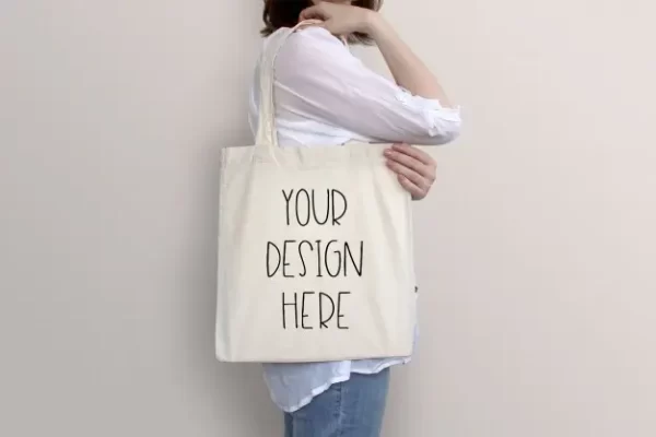 年轻女子手提袋挂肩帆布袋品牌Logo设计样机PS素材young woman is holding tote bag mockup